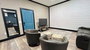 Un salon avec une porte bleue, un téléviseur et un grand mur blanc.