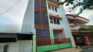 A multi-story residential building with a green and white facade, a gated entrance, and a satellite dish on the roof. - Hotel O Abang Homestay Syariah (Surabaya)