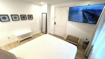 Een slaapkamer met een bed, een televisie, een deur en een aan de muur hangend schilderij.