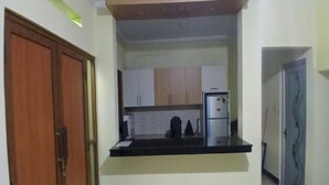 Una cocina compacta con encimera negra, armarios de madera y un refrigerador.
