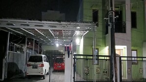 Un estacionamiento cerrado con un coche blanco y un coche rojo dentro.