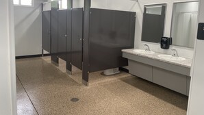 A modern bathroom with a row of dark stalls, a sink with a mirror, and a hand dryer. - Sleeping Cabin #12 perfect to sleep up to 12 guests No Water in Cabin (Letts)