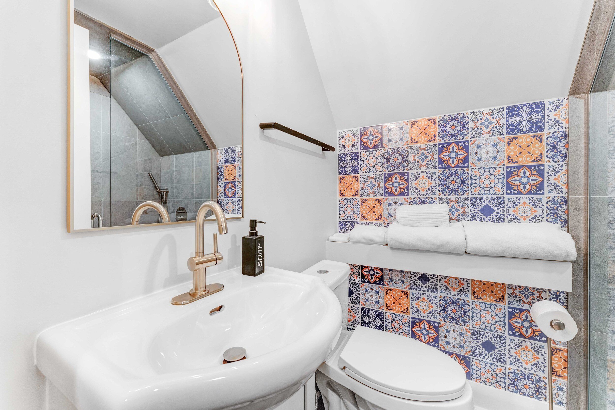 A bathroom with a white sink, a toilet, and a mirror.
