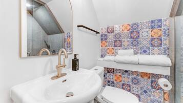 A bathroom with a white sink, a toilet, and a mirror.
