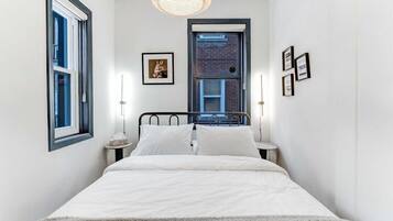 A bedroom with a bed, bedside tables, a window, and a door.