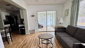 A modern living room with a grey sofa, a round coffee table, and a wooden floor. - The Teal Turtle  (Seminole)