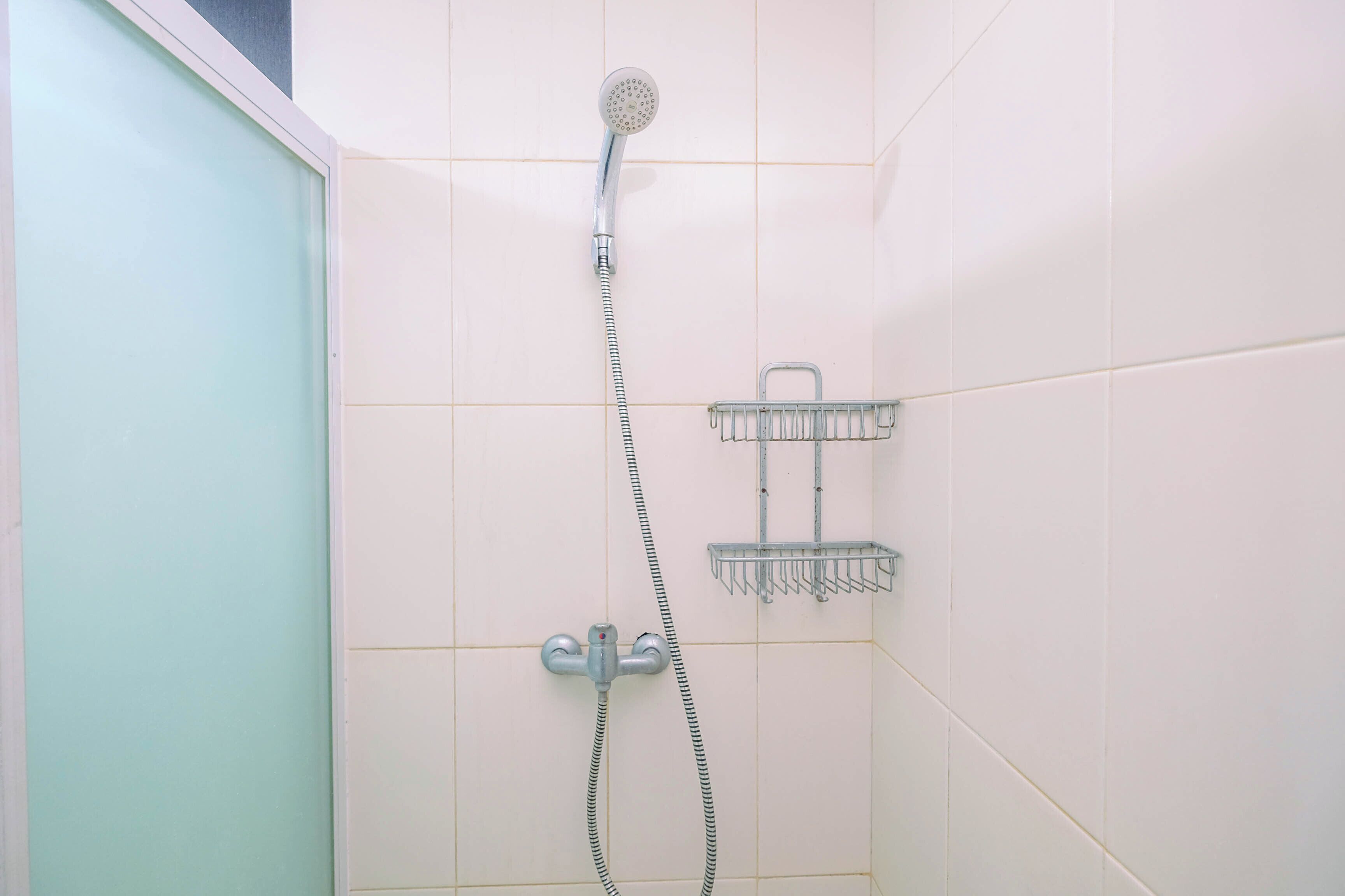 A shower with a handheld showerhead and a wall-mounted faucet.