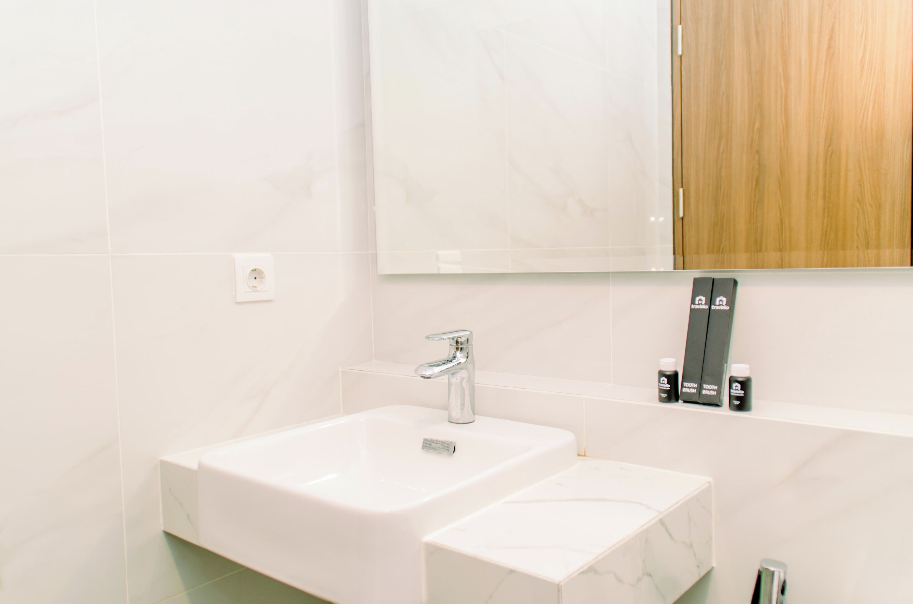 Un baño moderno con un lavamanos blanco, un espejo y un armario de madera.