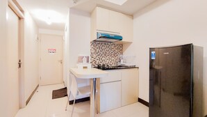 Una cucina compatta con un frigorifero nero, un piano di lavoro bianco e un backsplash piastrellato.