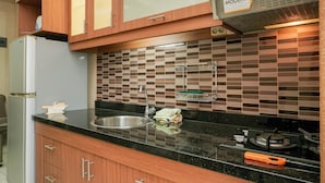 Een keuken met houten kastjes, een roestvrijstalen spoelbak, een betegelde achterwand en een gasfornuis.