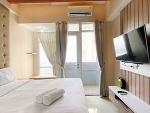 Une chambre d’hôtel équipée d’un lit, d’une télévision, d’une fenêtre avec des rideaux et d’un appareil de climatisation.