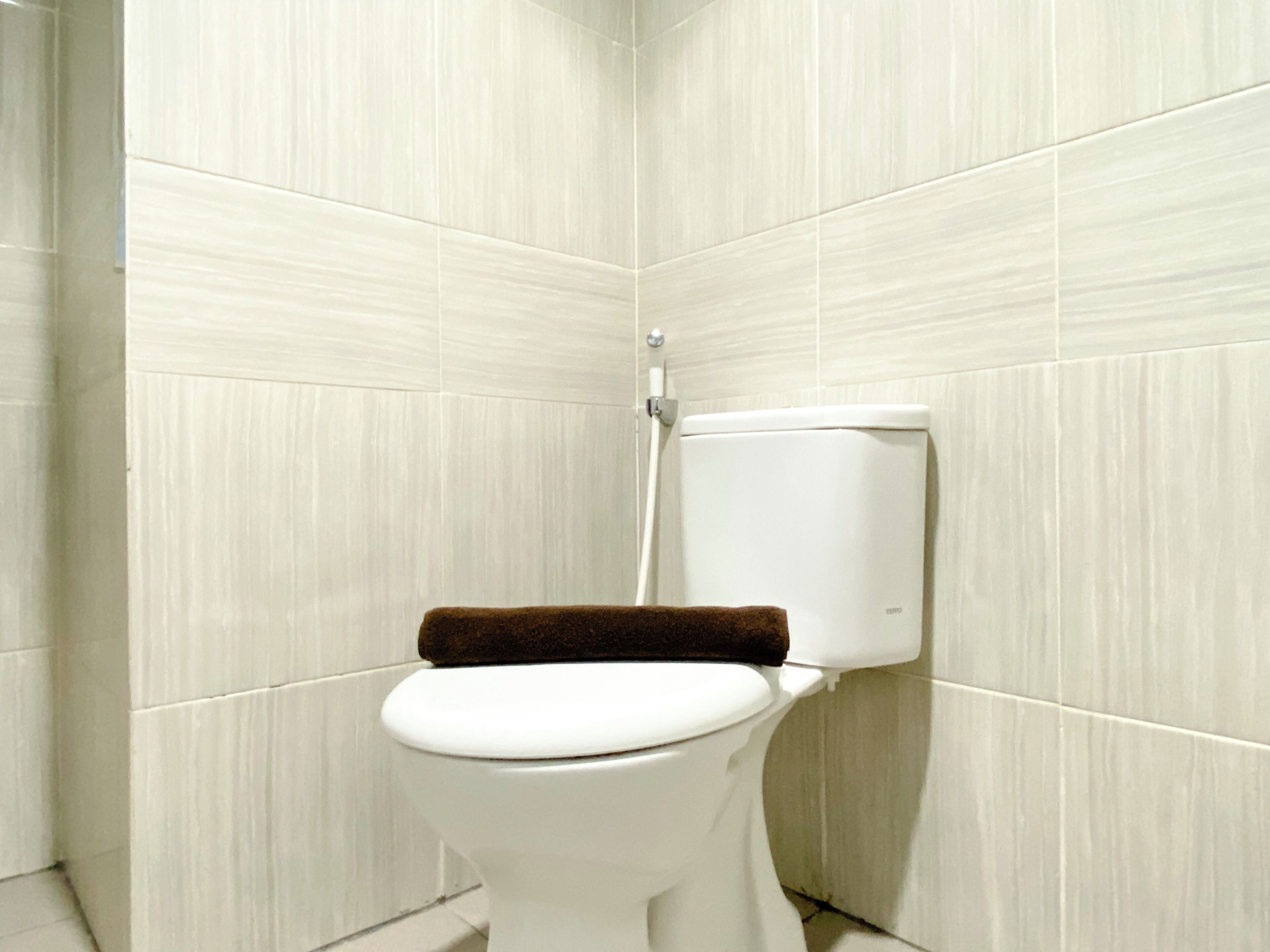 A white toilet in a bathroom with beige tiles.