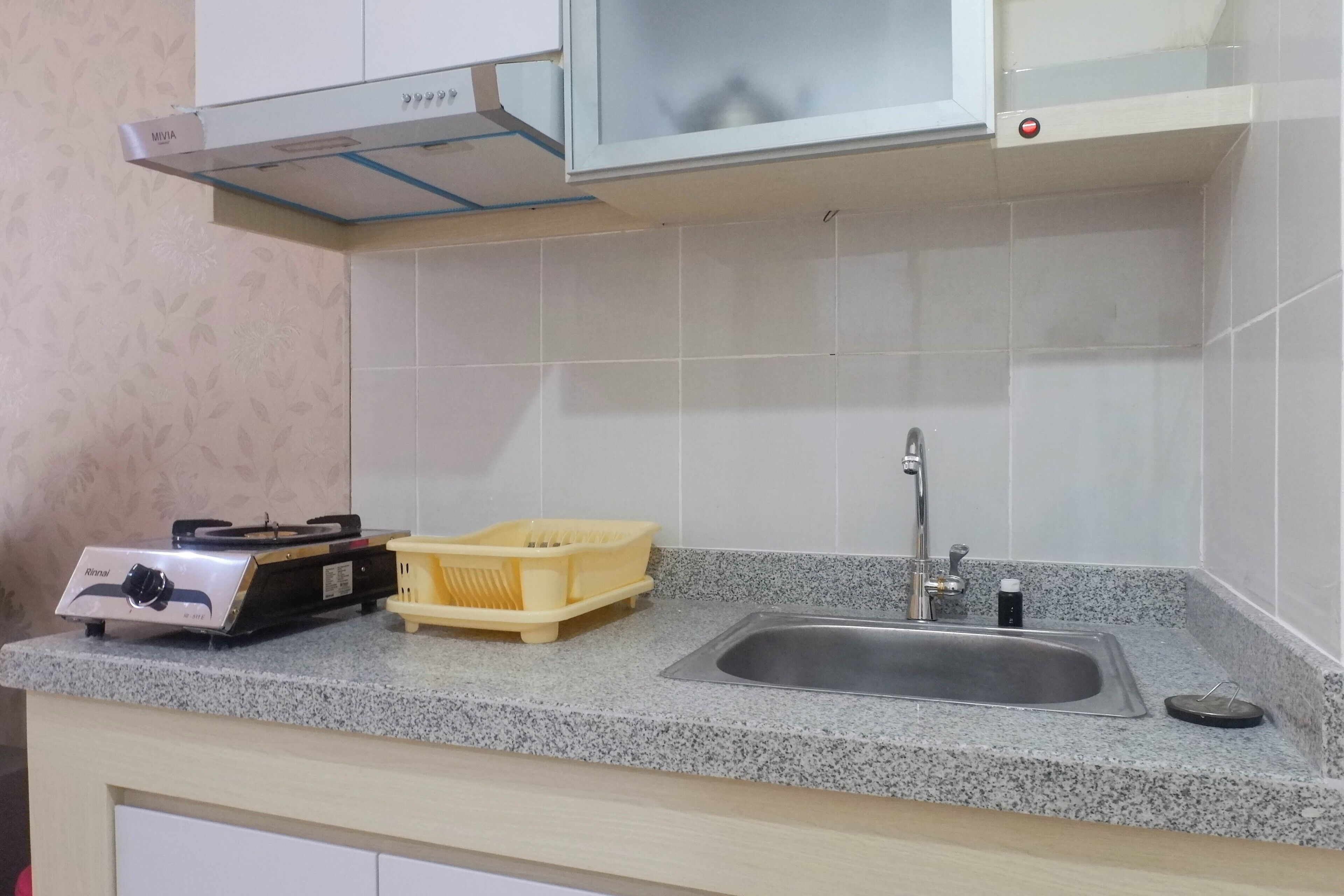 Une cuisine équipée d’une cuisinière à gaz, d’un évier et d’un égouttoir jaune.