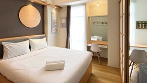 A modern hotel room with a large bed, a desk, and a chair. - Best Homey 1Br At 52Th Floor Vasanta Innopark Apartment (Cikarang)
