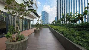 A modern building with a long, straight pathway lined with planters and greenery. - Nice And Comfort 1Br At 25Th Floor Samara Suites Apartment (Jakarta)