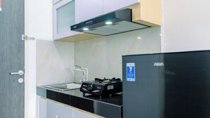 A modern kitchen with a stainless steel refrigerator, a gas stove, and a built-in oven. - Nice And Comfort Studio At Serpong Garden Apartment (Cisauk)