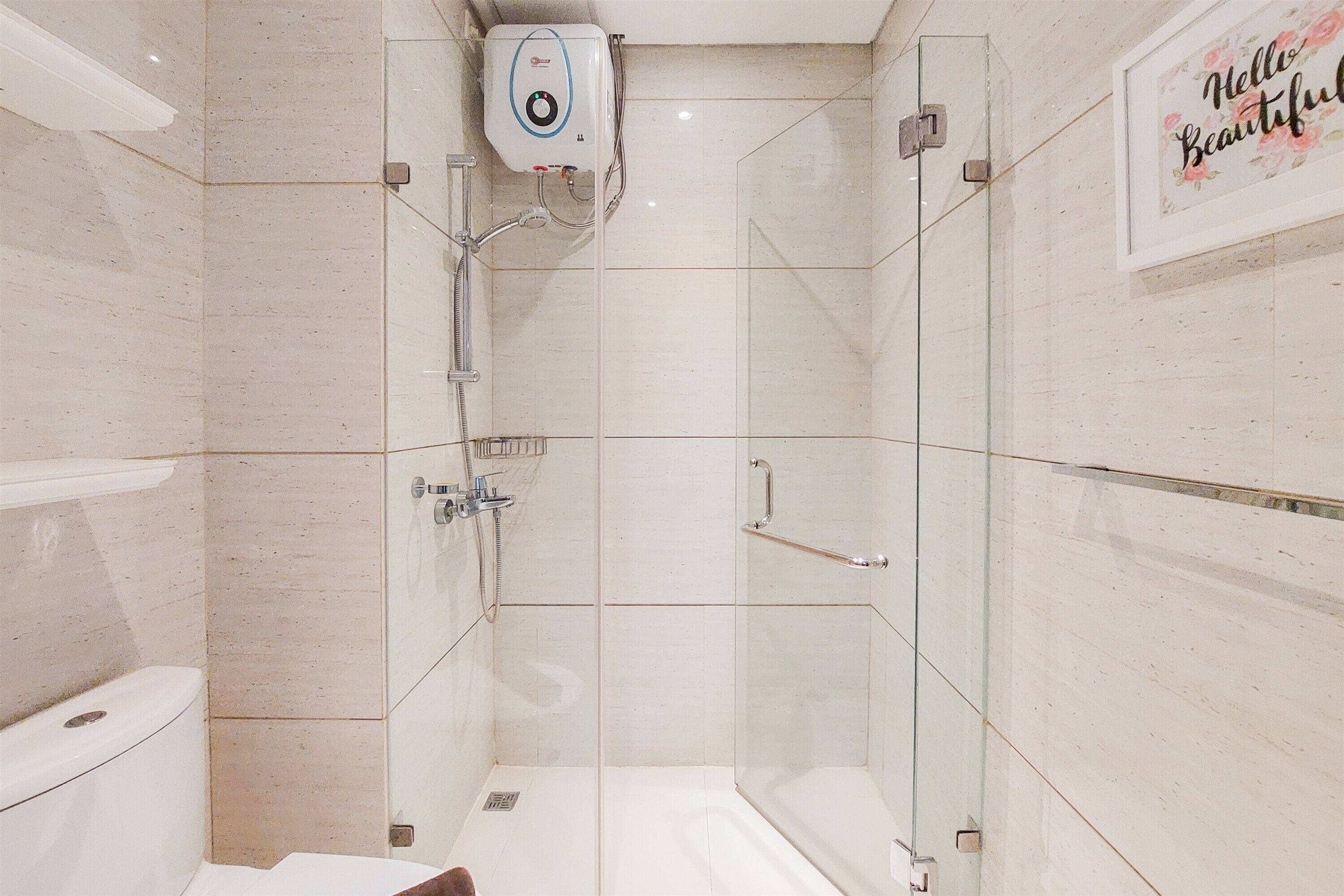 A modern bathroom with a glass-enclosed shower, a toilet, and a framed sign on the wall.