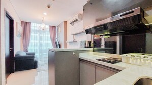 A modern kitchen with a built-in oven, microwave, and a stainless steel range hood. - Nice And Homey 1Br At Brooklyn Alam Sutera Apartment (South Tangerang)
