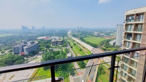 Ein Hochhaus mit mehreren Balkonen und Blick auf eine Stadtlandschaft, einschließlich Straßen und Grünflächen.