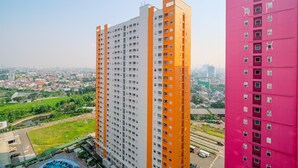 A high-rise building with multiple floors, a swimming pool, and a view of a cityscape in the background. - Fancy And Nice Studio (No Kitchen) At Green Pramuka City Apartment (Jakarta)