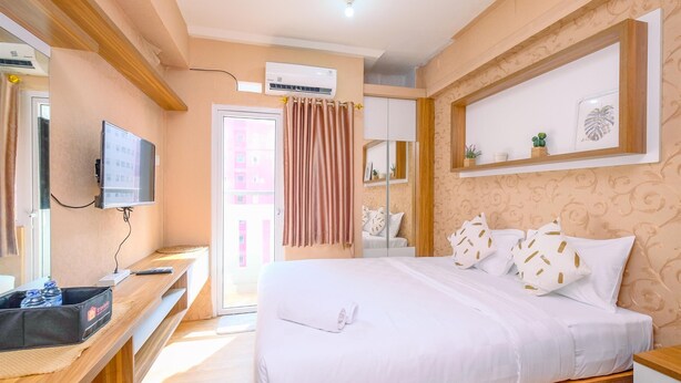 A hotel room with a bed, a TV, a desk, and a wardrobe. - Fancy And Nice Studio (No Kitchen) At Green Pramuka City Apartment (Jakarta)