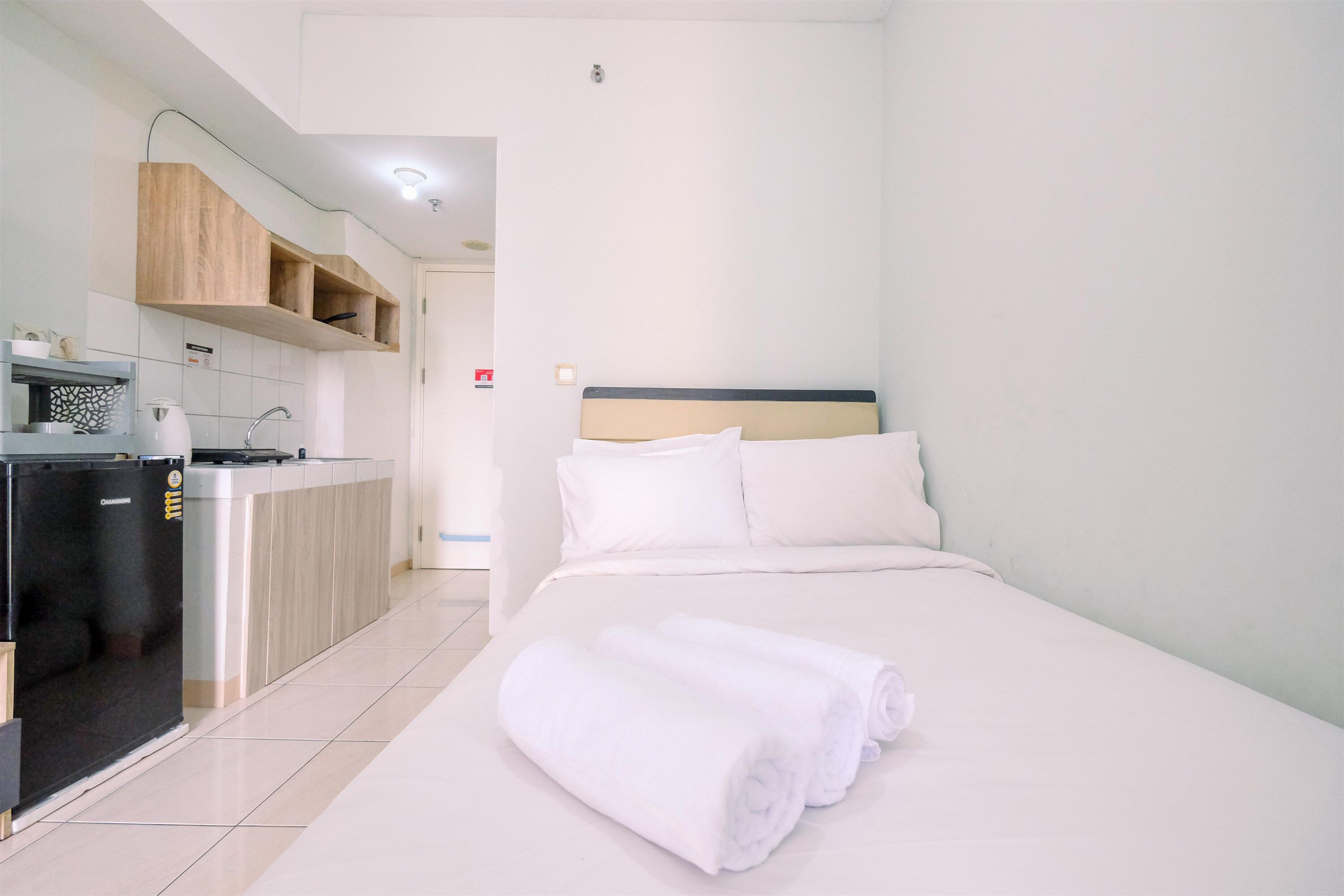 A hotel room with a bed, a kitchenette, and a bathroom.