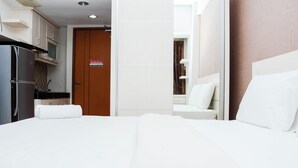 A hotel room with a bed, a bathroom, and a kitchenette. - Strategic And Comfy Studio Apartment At Margonda Residence 5 (Depok)
