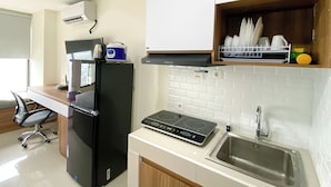A compact kitchen with a black refrigerator, a built-in stove, and a dish rack above the sink.