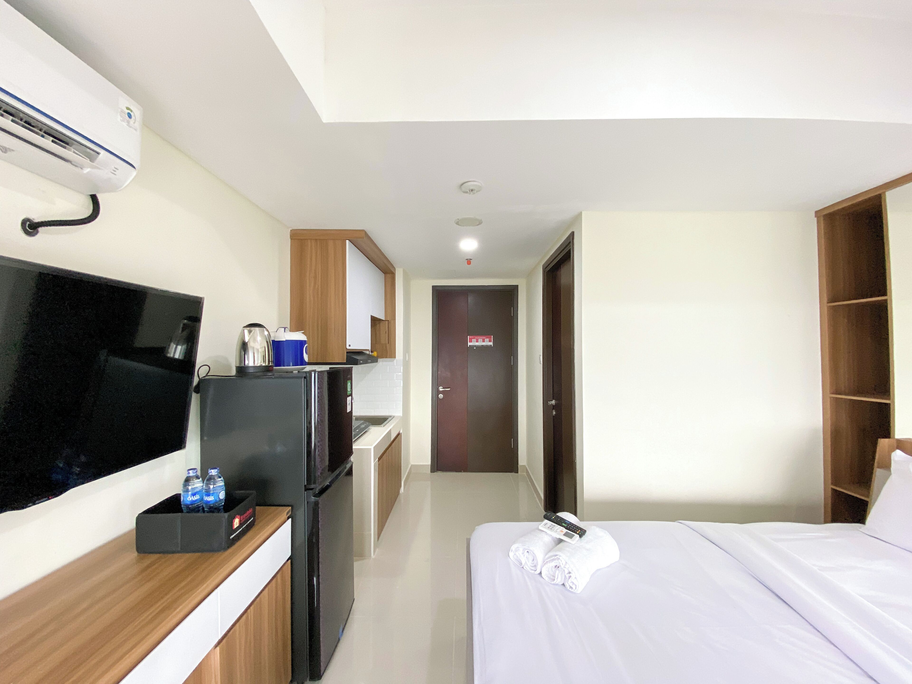 Una camera d'albergo con un letto, una TV, un frigorifero, un minibar e un armadio in legno.