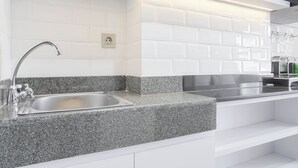 Una cocina moderna con encimera de granito, lavamanos de acero inoxidable y azulejos blancos tipo metro.