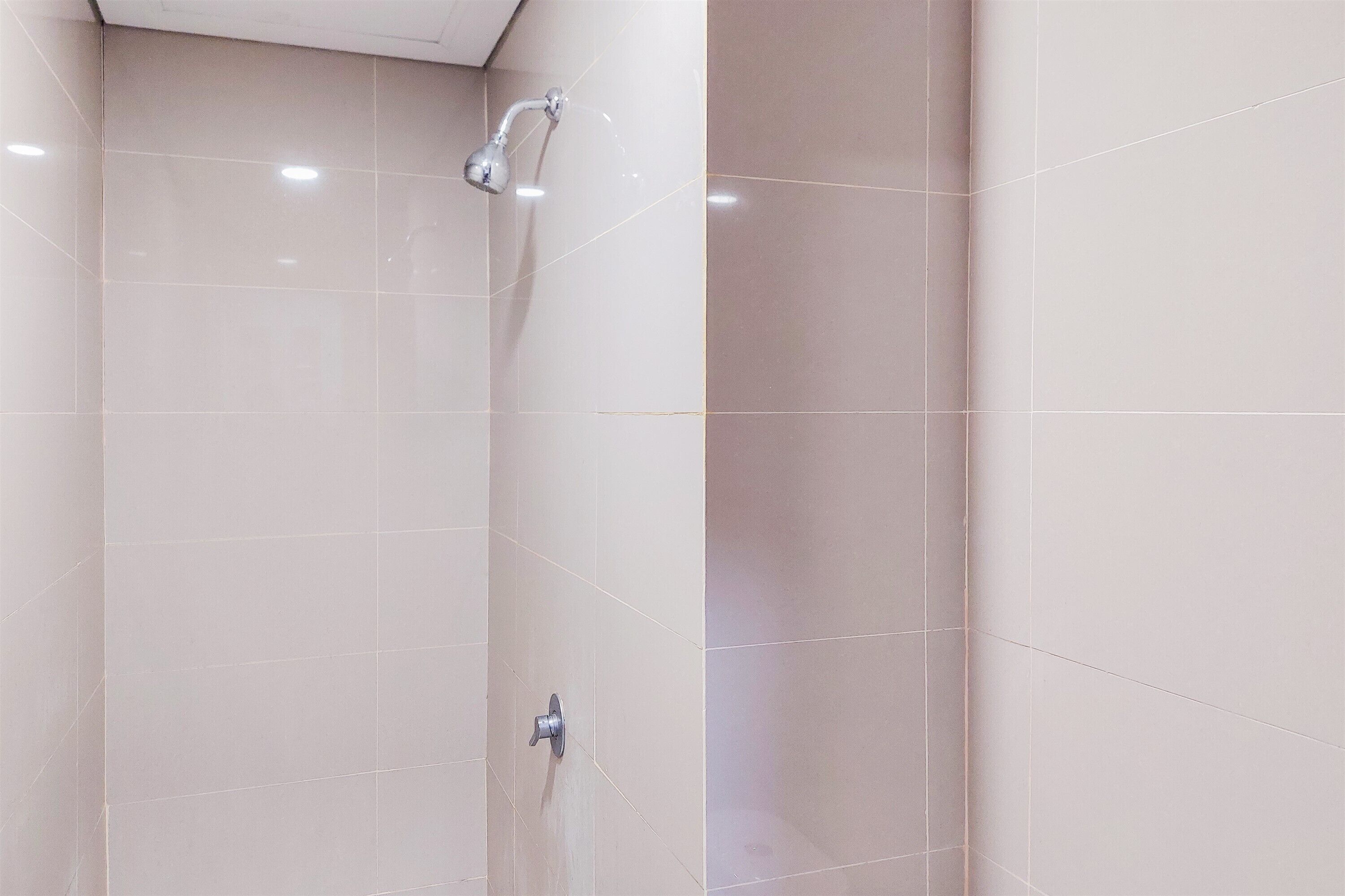 A shower area with a handheld showerhead and a wall-mounted control valve.