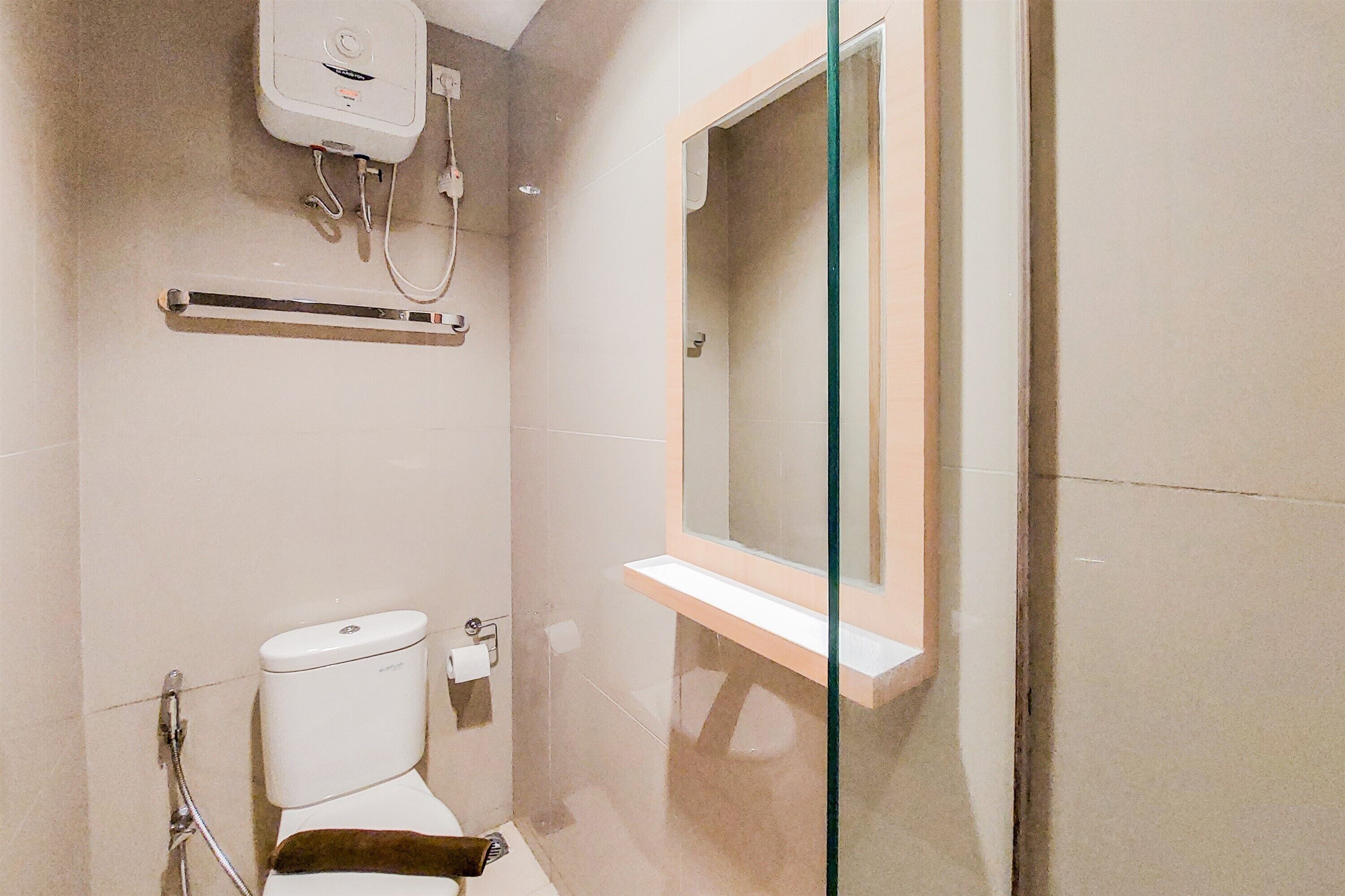 A bathroom with a toilet, a glass shower enclosure, a towel rack, and a mirror.