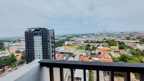 A high-rise building with a modern design, overlooking a cityscape with various buildings and greenery.