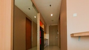 A narrow hallway with a sliding door, a refrigerator, and a wooden shelf.