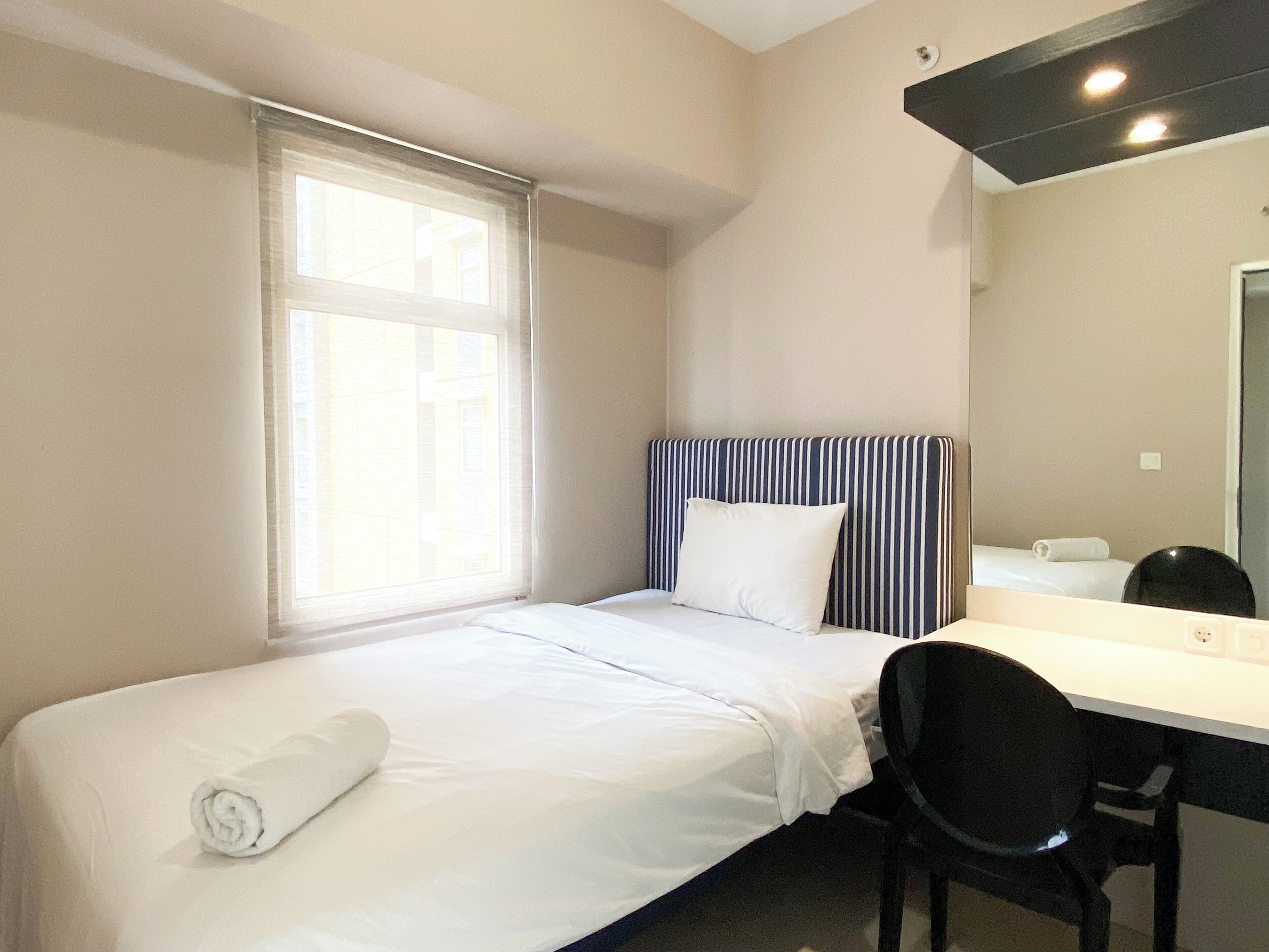 Una habitación de hotel con una cama individual, un escritorio y una silla.