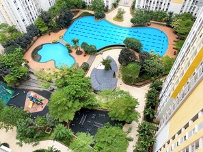 A residential complex with a swimming pool, playground, and surrounding greenery. - Warm Living And Homey 2Br At Springlake Summarecon Bekasi Apartment (Bekasi)