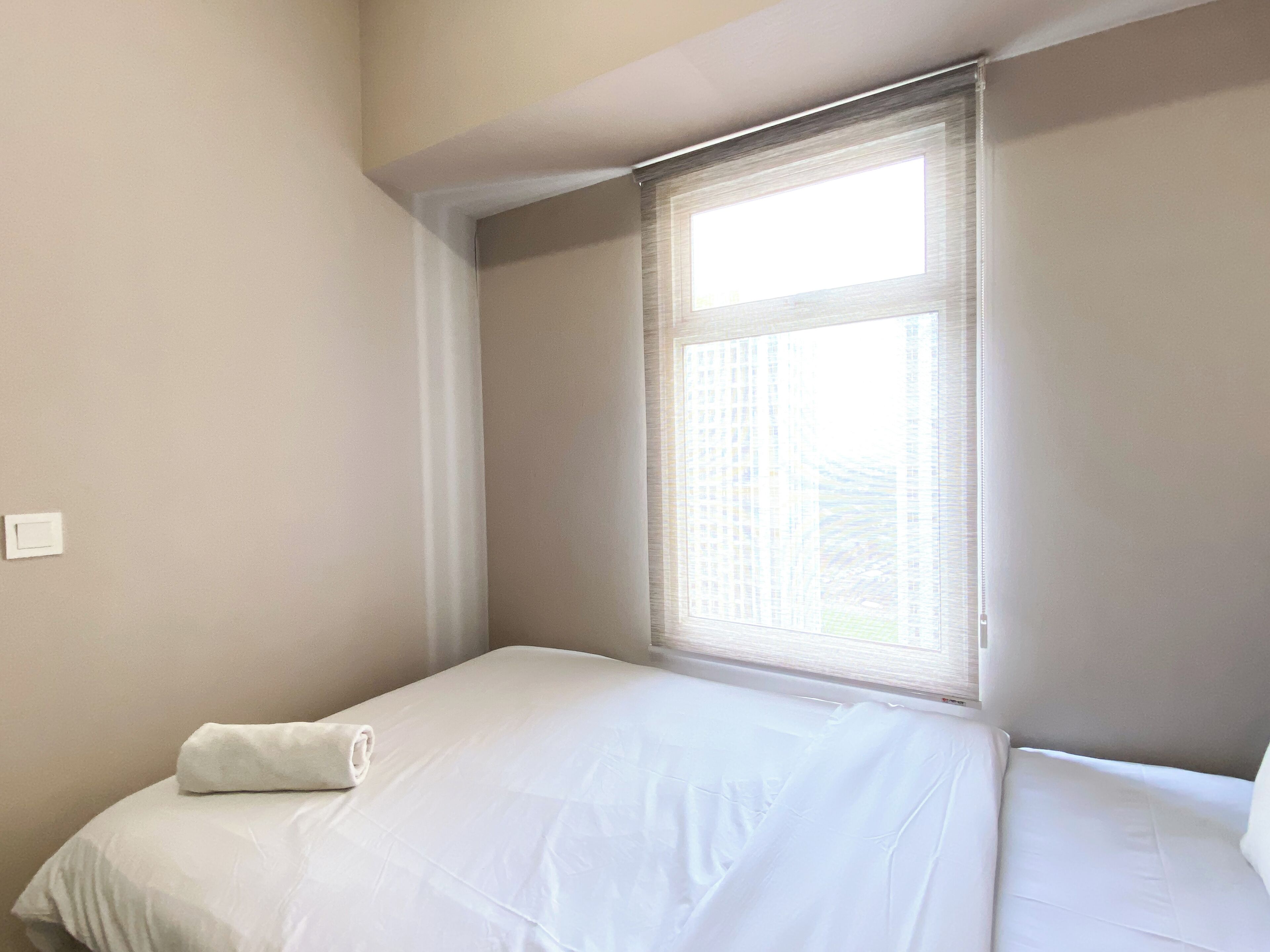 A small, neatly made bed in a room with a window.