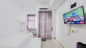 A hotel room with two beds, a TV on the wall, and a shower area. - Restful And Comfortable Studio Serpong Garden Apartment (Cisauk)