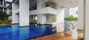 A modern building with a swimming pool, glass railings, and a view of surrounding high-rise buildings.