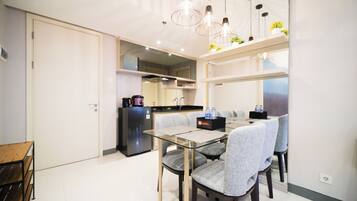 A modern kitchen with a dining area, including a table with chairs, a refrigerator, and a water dispenser.