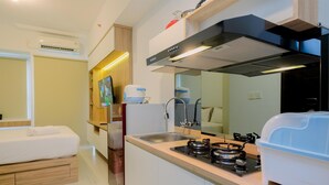 Une cuisine compacte équipée d’une cuisinière à gaz, d’un évier et d’appareils électroménagers modernes.