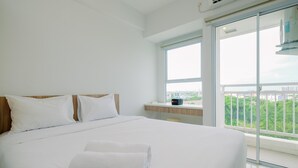 Une chambre d’hôtel avec un grand lit, une petite table et une vue sur la verdure depuis un balcon.