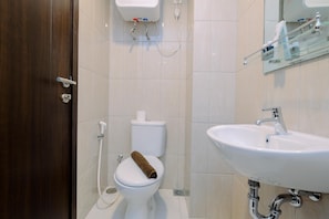 A bathroom with a toilet, sink, and a mirror. - Comfy And Best Deal Studio At Citra Living Apartment (Jakarta)