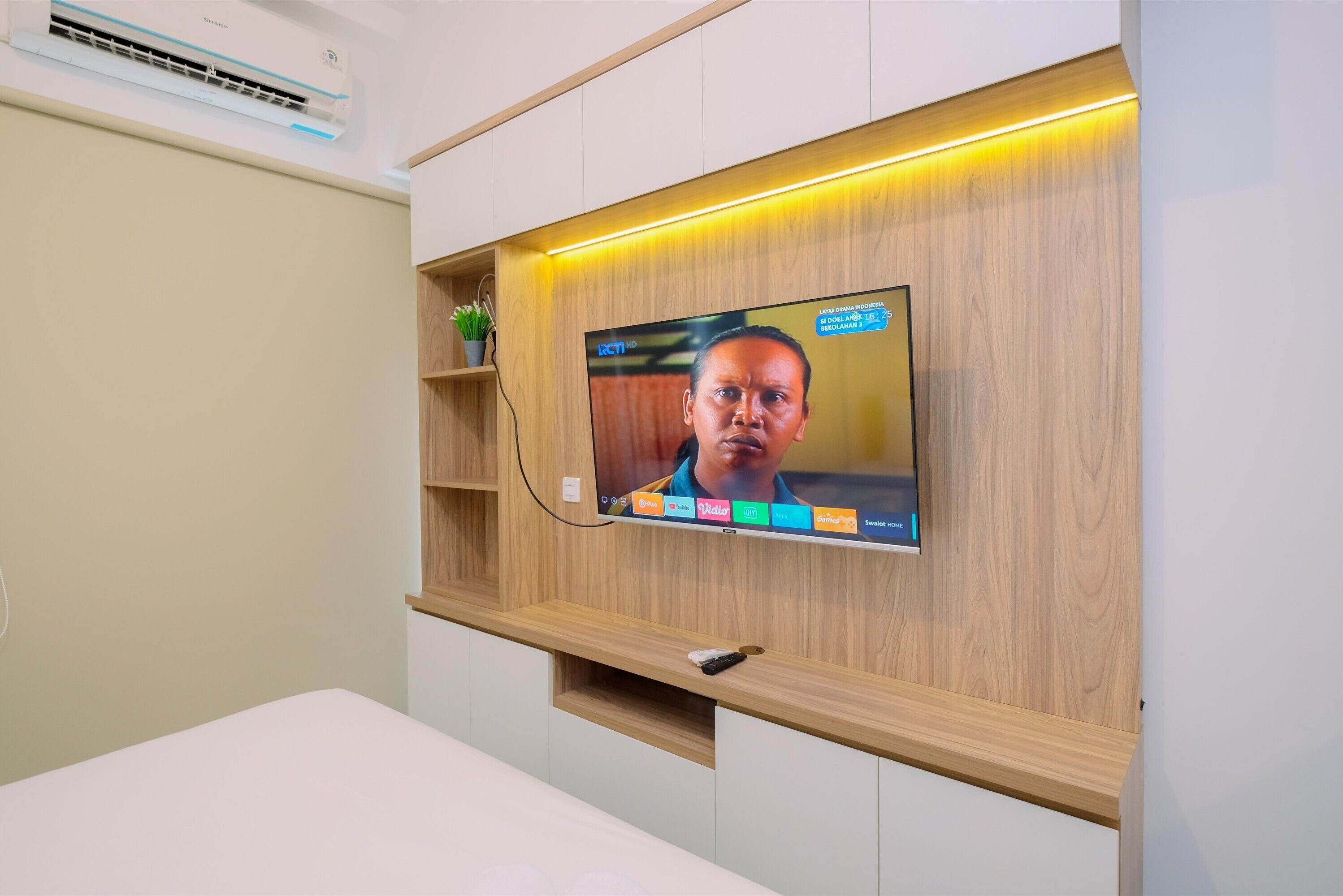 A television mounted on a wooden wall with a shelf below.