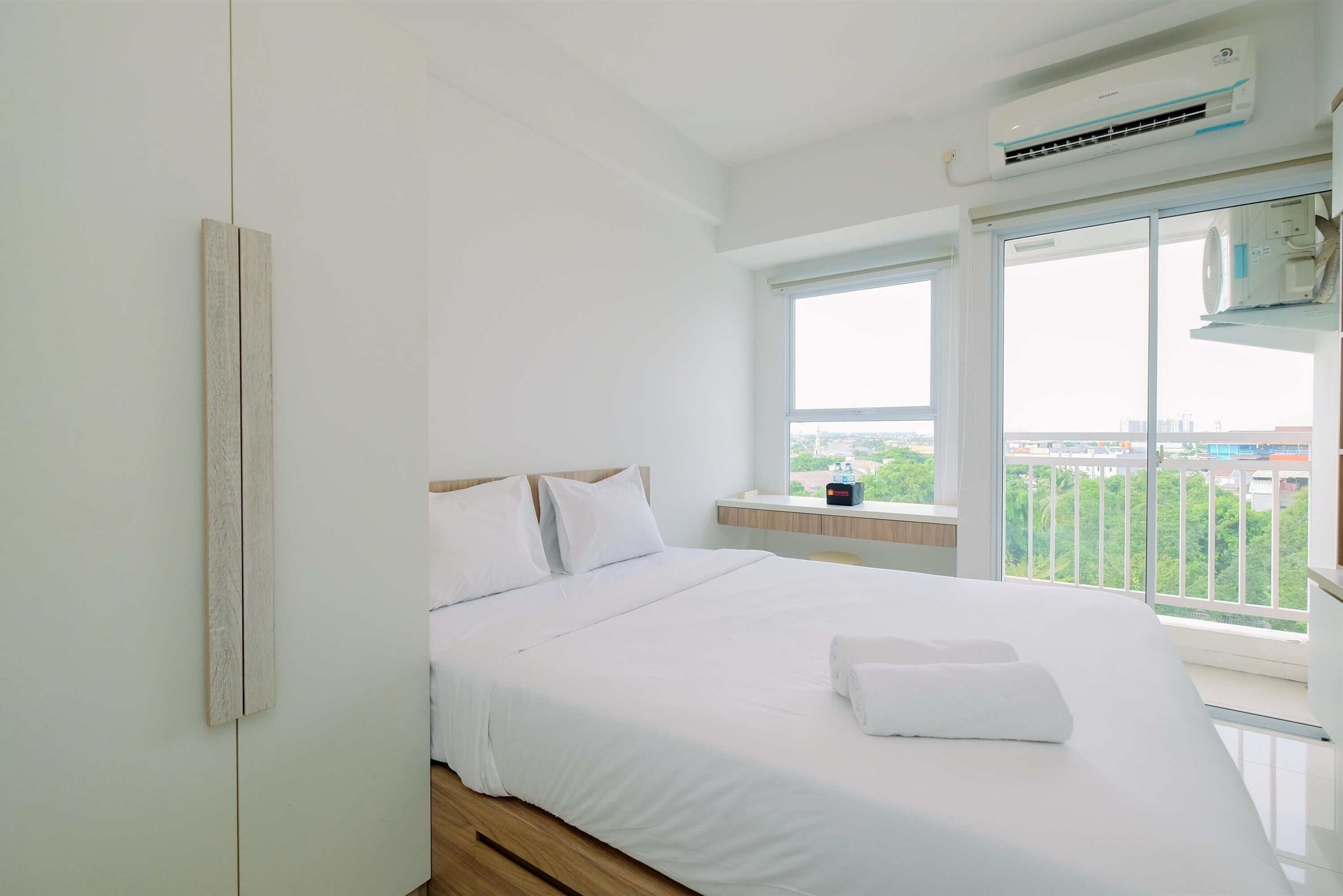 Een slaapkamer met een groot bed, wit beddengoed, een raam met uitzicht en een airconditioning.