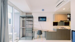 Ein modernes Hotelzimmer mit Bett, Schreibtisch, Sessel, Fernseher und einer Küchenzeile.