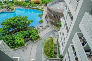 A modern building with a swimming pool surrounded by greenery. - Homey And Wonderful Studio At West Vista Apartment (Jakarta)