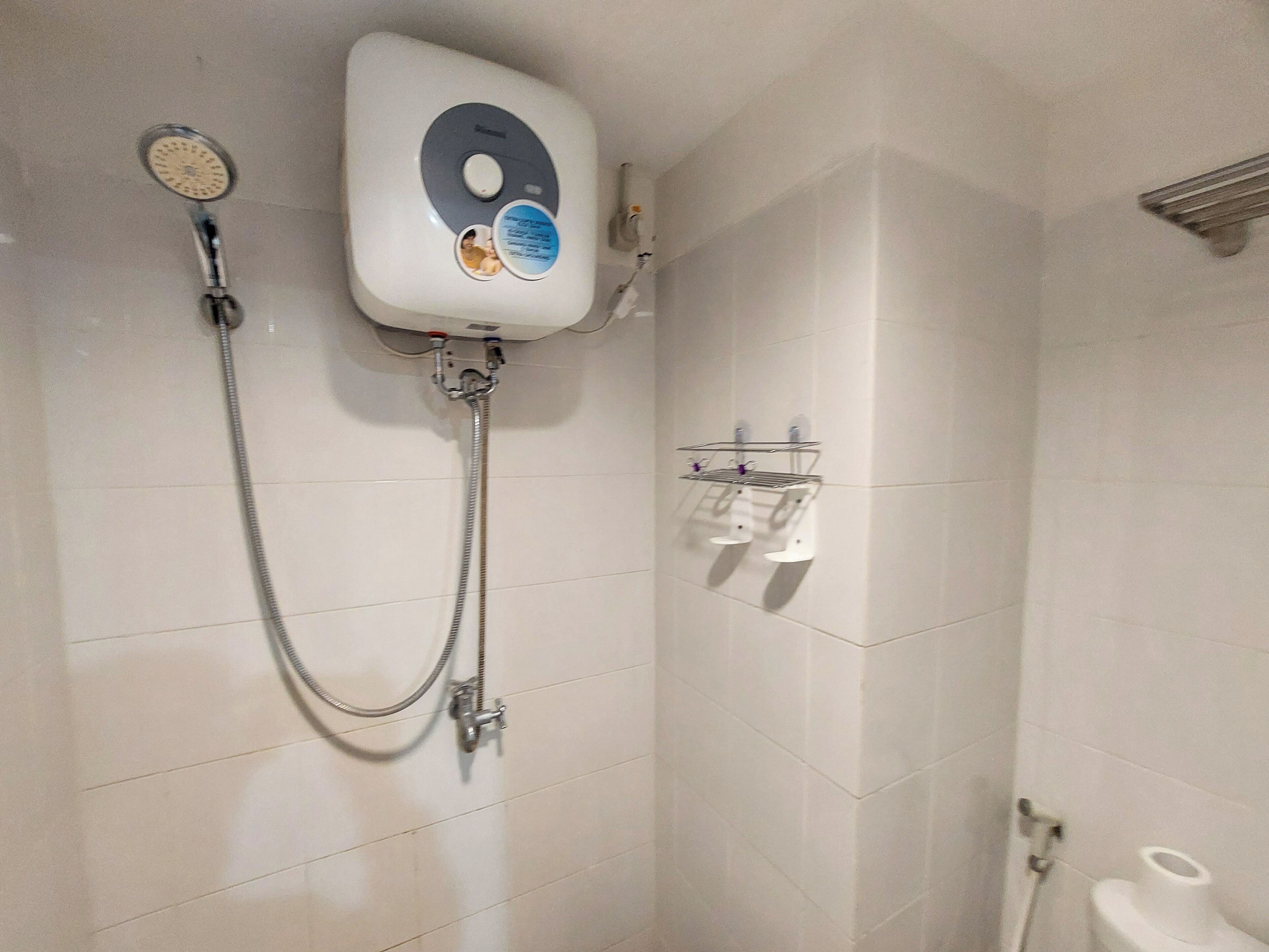 A bathroom with a shower, a toilet, and a hand dryer.
