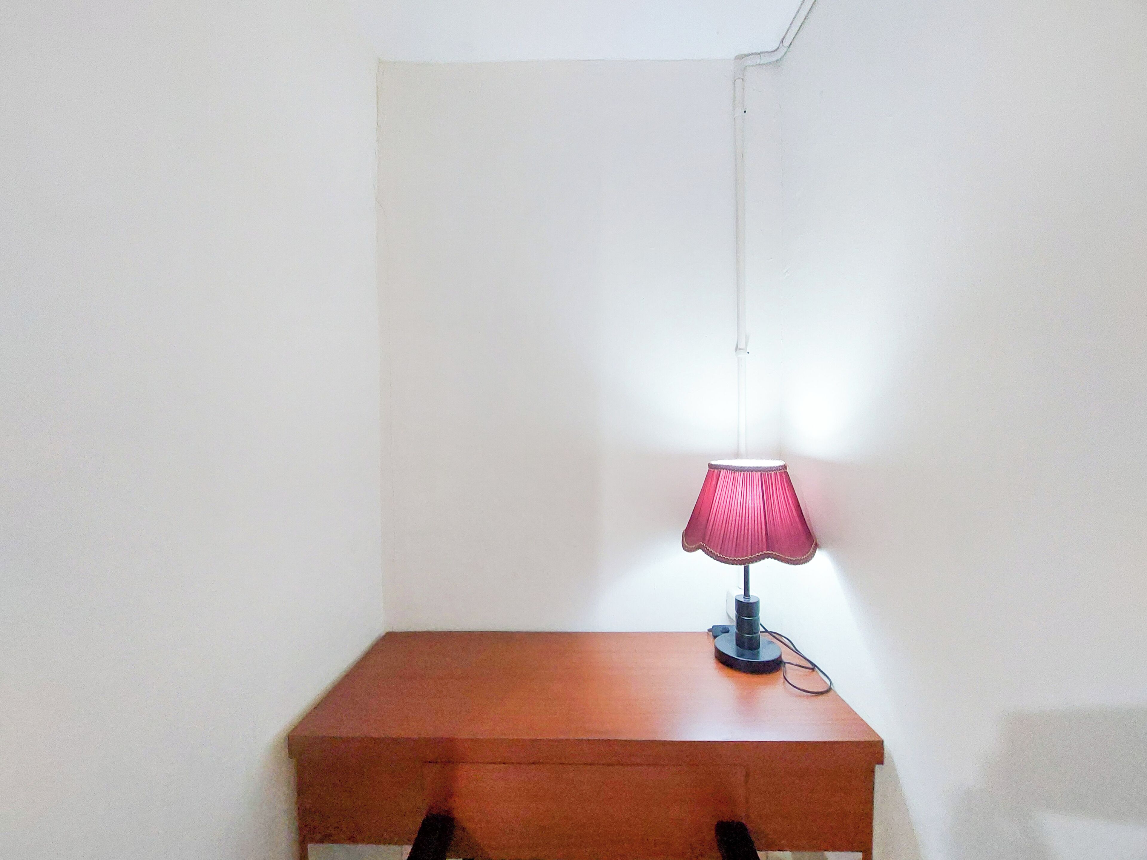 Ein kleiner Holztisch mit einer einzelnen rosa Lampe darauf.