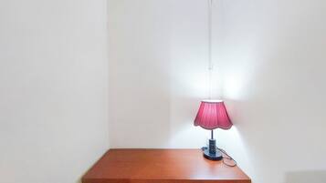 Una pequeña mesa de madera con una lámpara rosa individual.